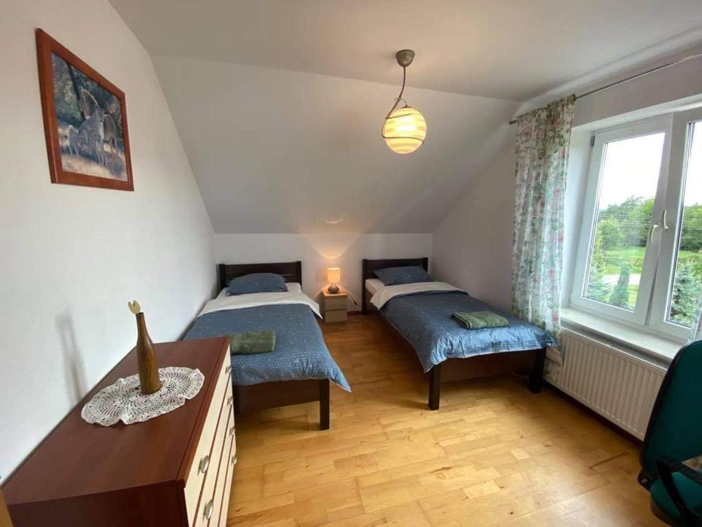 a bedroom with two beds and a table and a window at Noclegi Dobry Kwadrat in Bodzentyn
