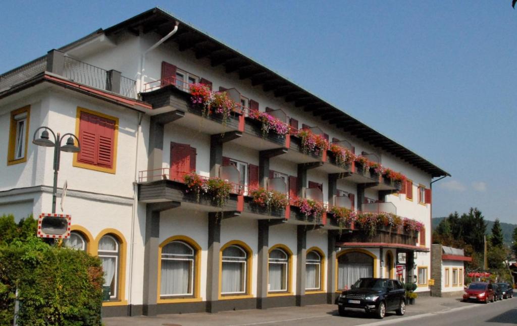 een gebouw met bloembakken op de balkons bij Hotel Velden Bacherlwirt in Velden am Wörthersee