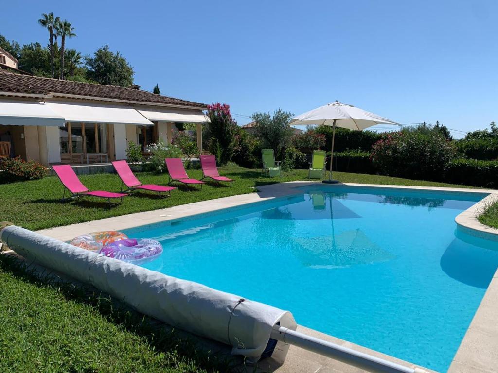 a swimming pool with pink chairs and an umbrella at Bed & Breakfast Les LILLAS in Saint-Jeannet