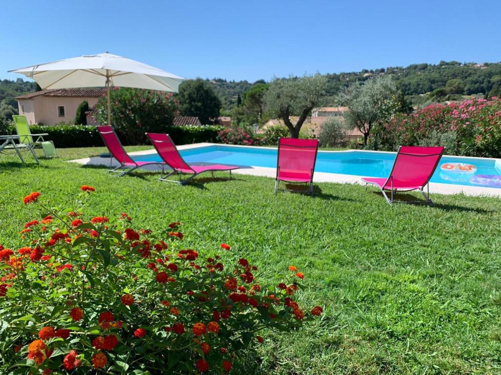 a group of chairs sitting in the grass near a pool at Bed & Breakfast Les LILLAS in Saint-Jeannet