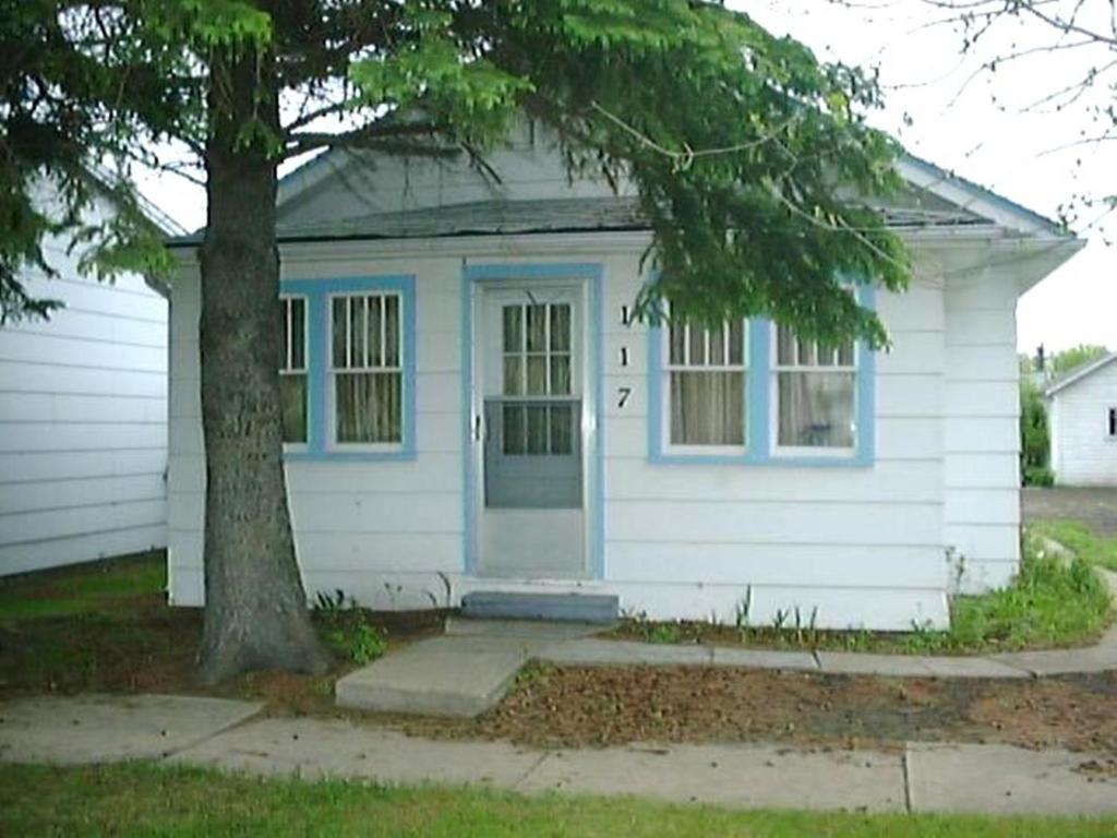 ein weißes Haus mit einem Baum davor in der Unterkunft Holiday Cottage in Canora