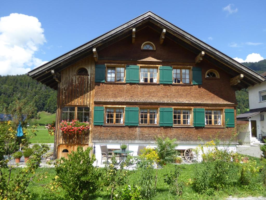 a large wooden house with green shutters at Ferienwohnung auf der Scheibe in Bezau