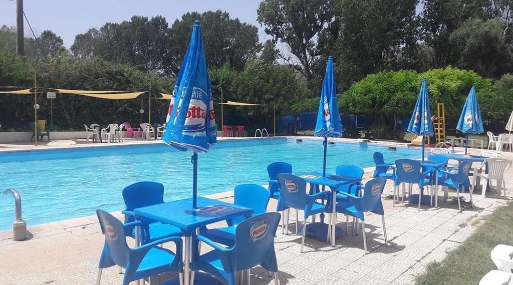 um grupo de mesas e cadeiras azuis ao lado de uma piscina em B&B RosAngelo em Mirabella Imbaccari