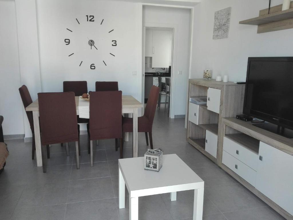 comedor con mesa y reloj en la pared en Apartamento Aliste, en Nerja