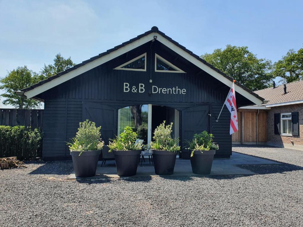 een zwart gebouw met potplanten ervoor bij B&B Drenthe in Westerbork
