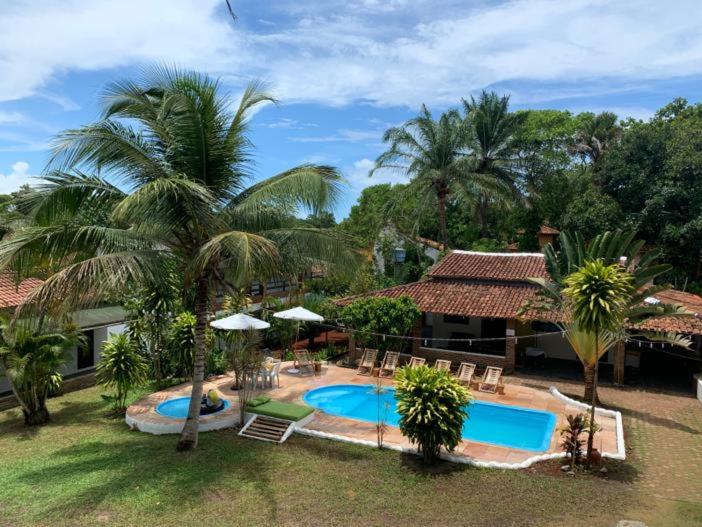 um resort com piscina e palmeiras em Pousada Bella Vida em Arraial d'Ajuda