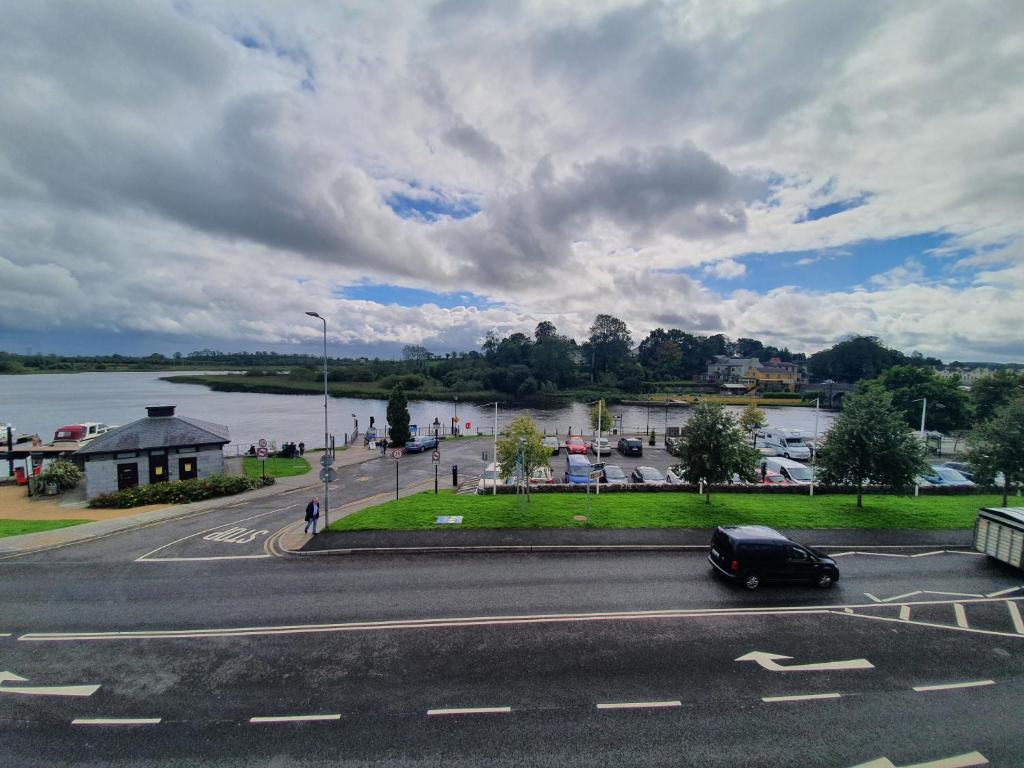 Ein schwarzes Auto fährt eine Straße entlang eines Flusses in der Unterkunft Waterfront View Apartment in Carrick on Shannon