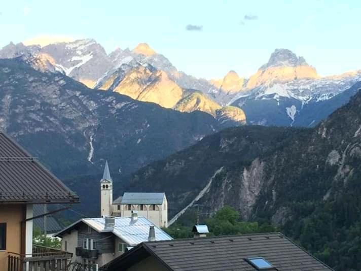 a view of a mountain range with a building and a church at Pit Stop Cadore in Valle di Cadore