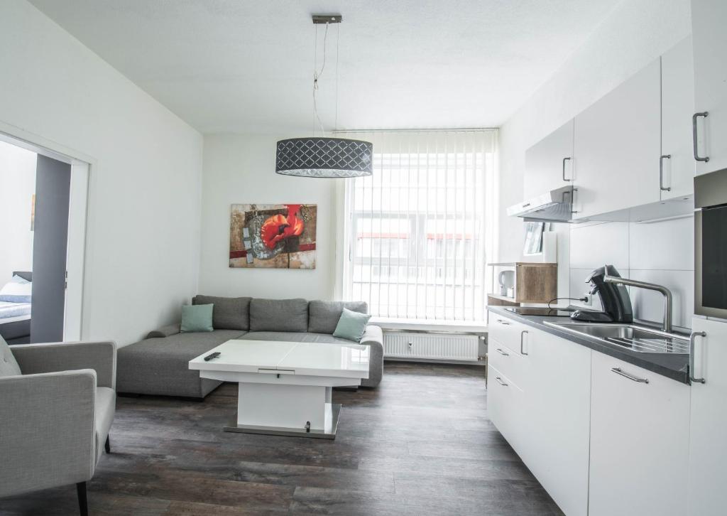a white living room with a couch and a kitchen at Central Apartments Aalen in Aalen