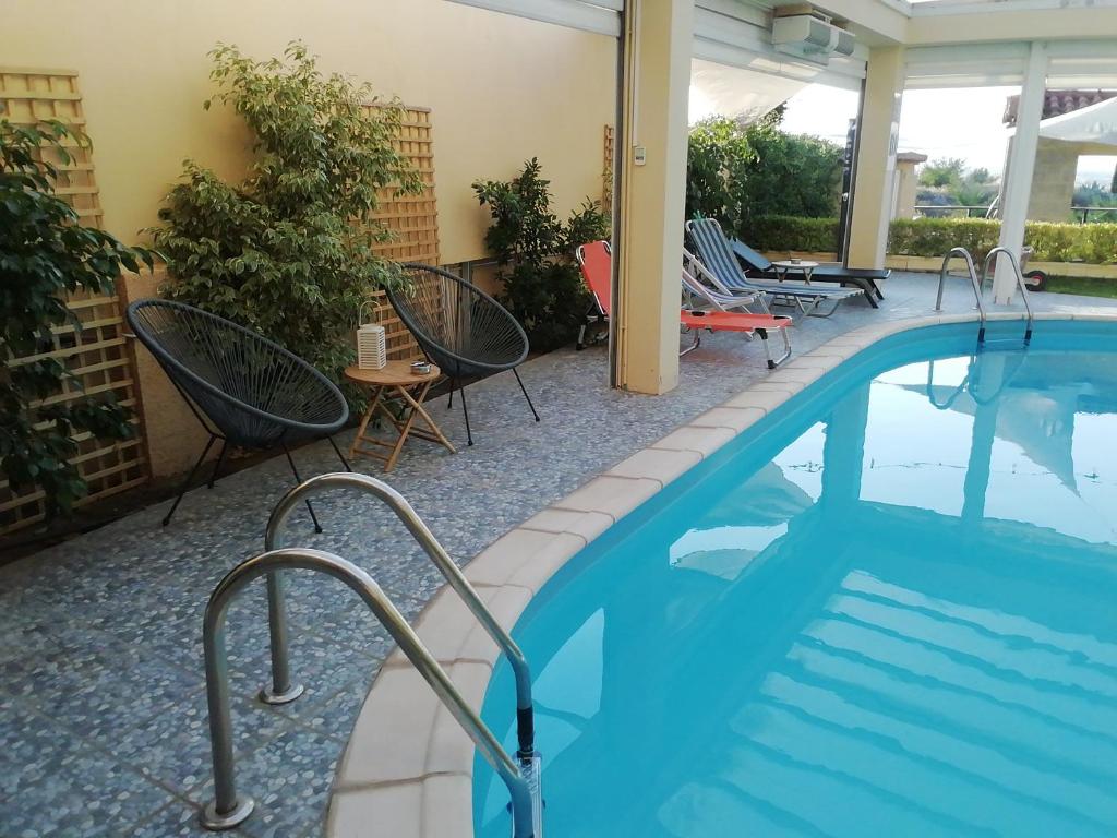 una piscina con sillas y una mesa junto a un edificio en Stone Guesthouse, en Korinthos