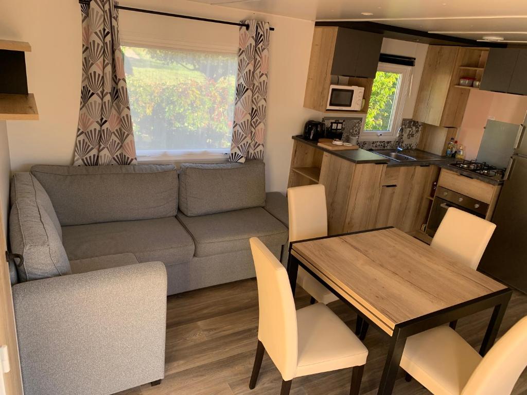 ein Wohnzimmer und eine Küche mit einem Tisch und einem Sofa in der Unterkunft Mobilhome 3 étoiles in Embrun