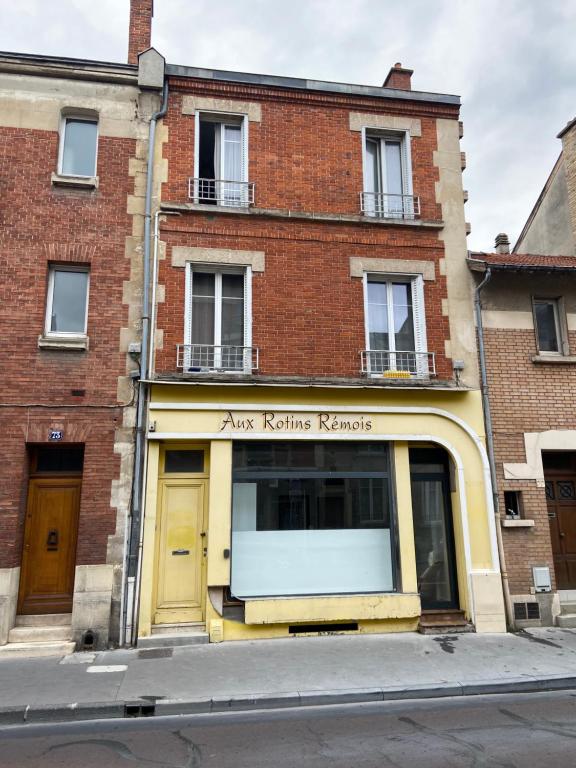 a store front of a brick building with a yellow door at LES ROTINS - Logements Climatisés - Cathédrale à 2 pas in Reims