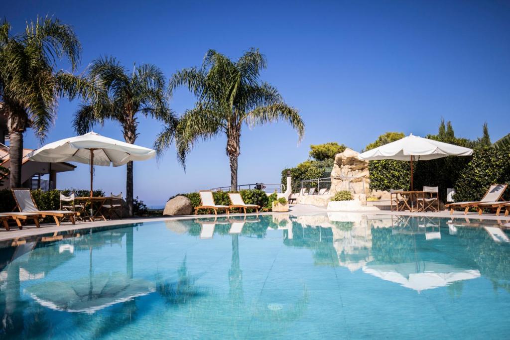 una piscina con sillas y sombrillas en L' Arcobaleno Resort en Capo Vaticano
