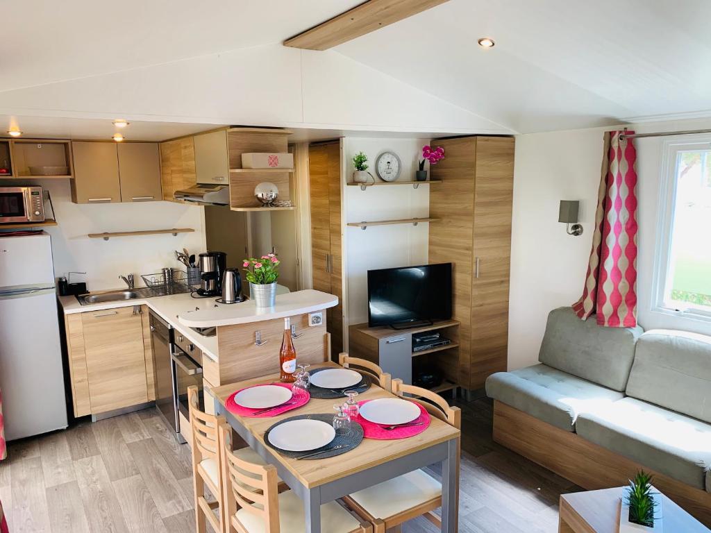 cocina pequeña y sala de estar con mesa y sillas en Mobil home excellence le lac des rêves 4* LATTES en Lattes