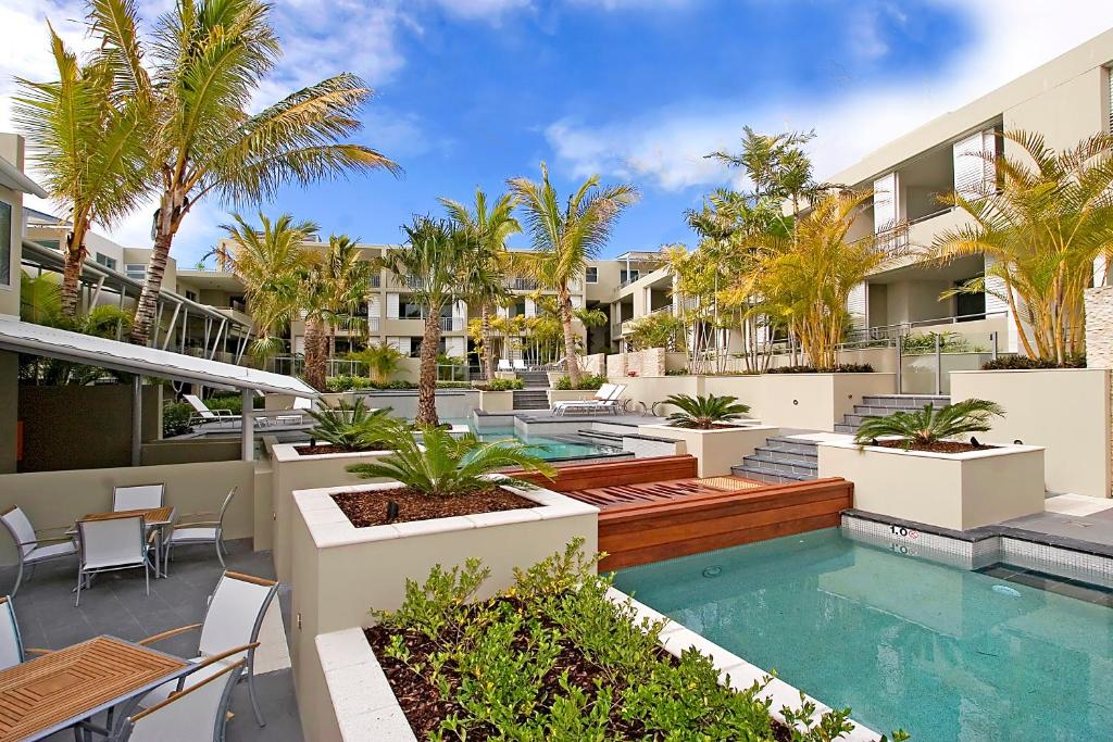 a courtyard with a swimming pool and palm trees at The Beach Cabarita in Cabarita Beach