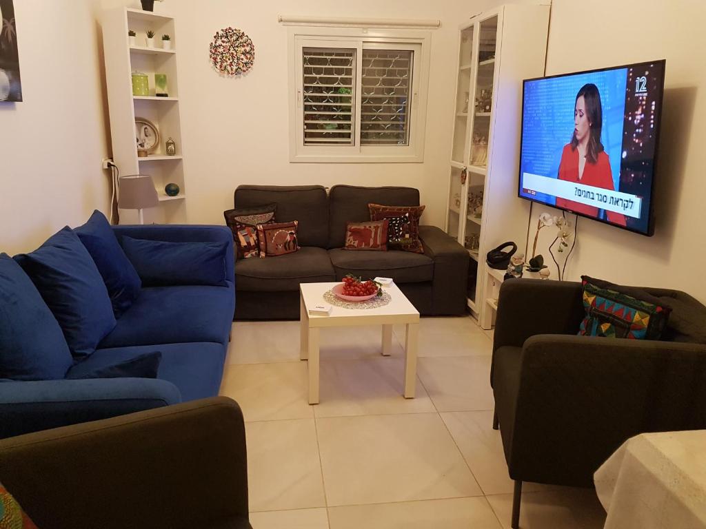 a living room with a couch and a tv at Blau Guesthouse in Netanya