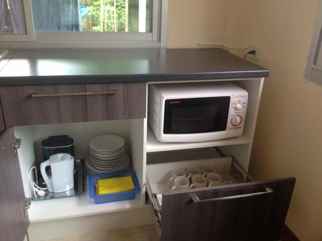 a kitchen with a microwave and some plates and dishes at Janson's House in Ban Mae Kon