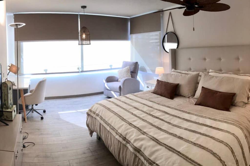 ein Schlafzimmer mit einem großen Bett und Stühlen sowie einem Fenster in der Unterkunft Precioso departamento en Los Dominicos in Santiago