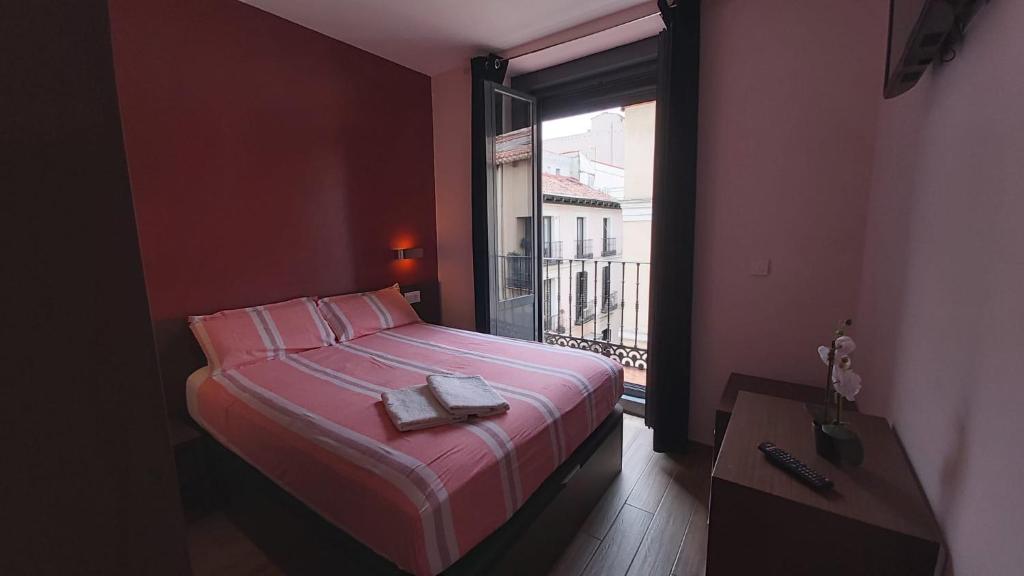 1 dormitorio con cama con sábanas rosas y ventana en Hostal Corazón de Madrid, en Madrid