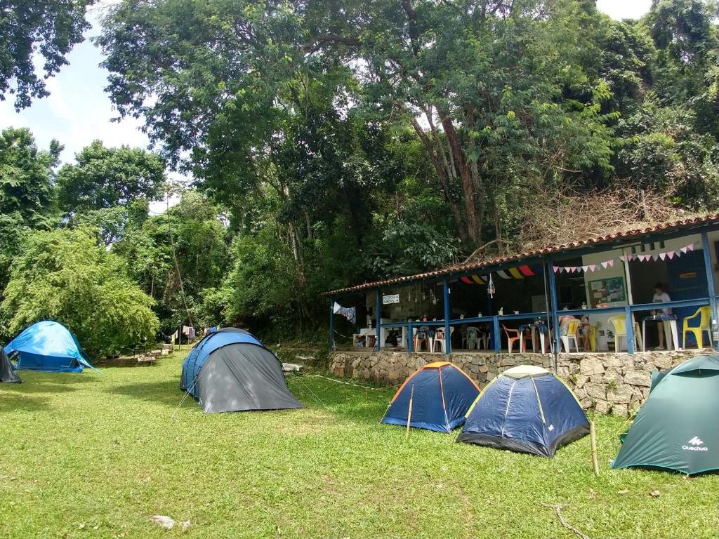 a group of tents in the grass in front of a building at Camping Flamboyant in Ilhabela