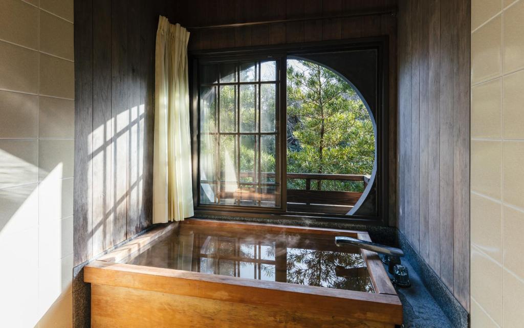 a bathroom with a bath tub with a window at Futsukaichi Hot Spring - Daimaru Besso in Chikushino