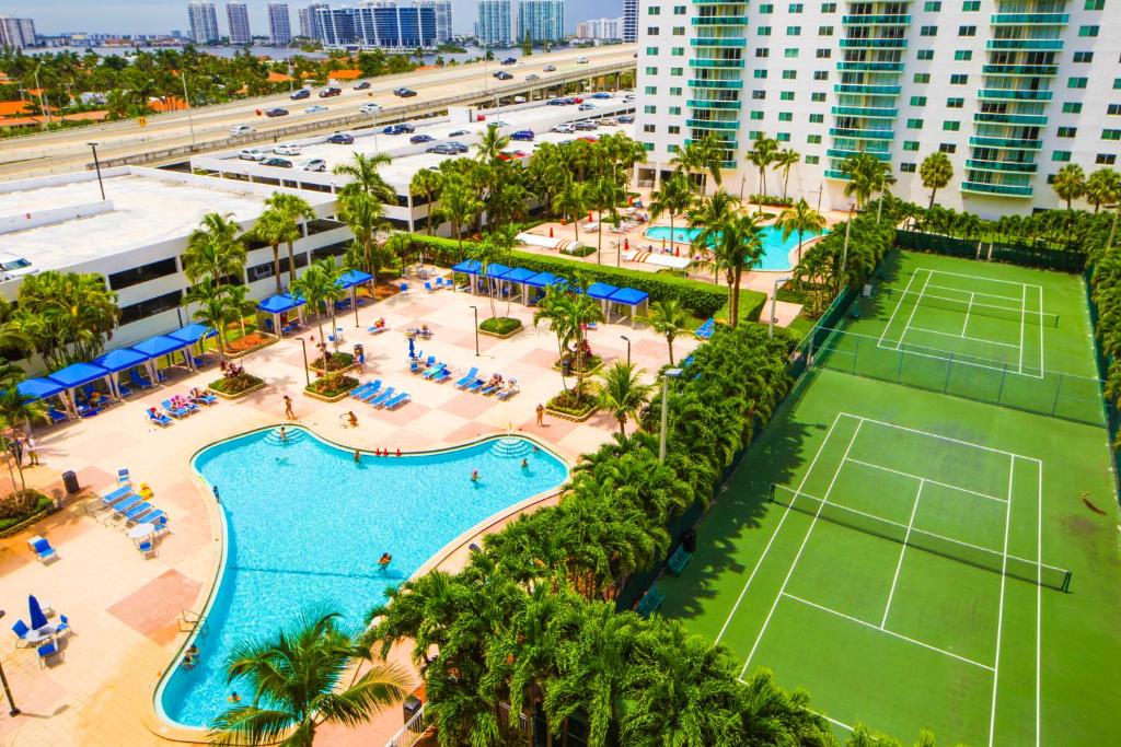 Sunny Isles Ocean Reserve Condo Apartments في ميامي بيتش: اطلالة جوية على منتجع مع ملعب تنس