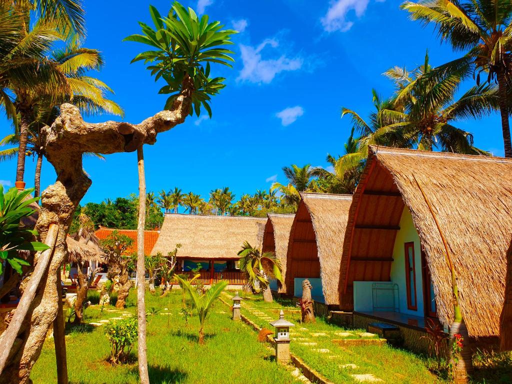 a group of cottages with palm trees in the foreground at Lempeh Jungle Cottage in Nusa Penida