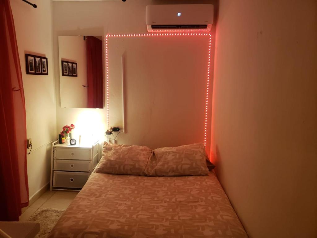 Aché Tropical Studio@white-Red في سان خوان: غرفة نوم مع سرير مع ضوء على الحائط