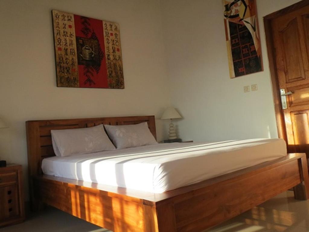 1 dormitorio con 1 cama con marco de madera en Bali Sari Homestay, en Amed