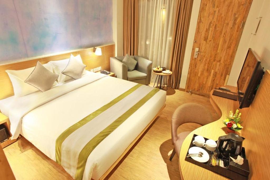 una camera d'albergo con un grande letto e un tavolo di Liberta Hotel Jimbaran a Jimbaran