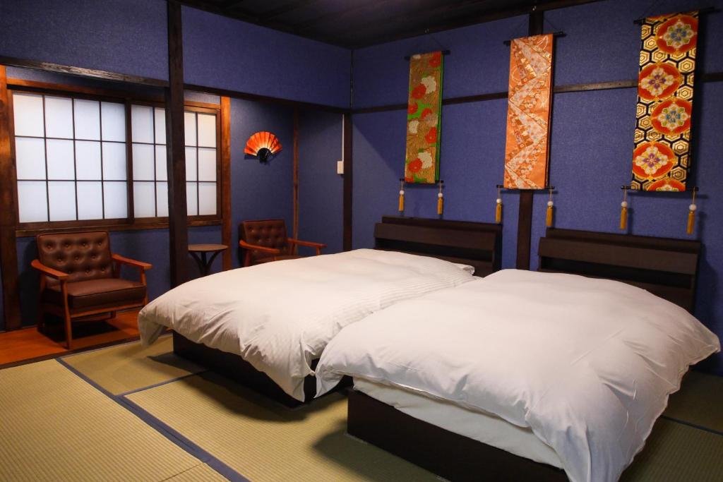 2 Betten in einem Zimmer mit blauen Wänden und Fenstern in der Unterkunft Kanazawa Machiya Aburaya in Kanazawa