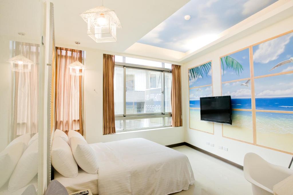 a bedroom with a bed and a tv and windows at Dong Men Hotel in Taipei