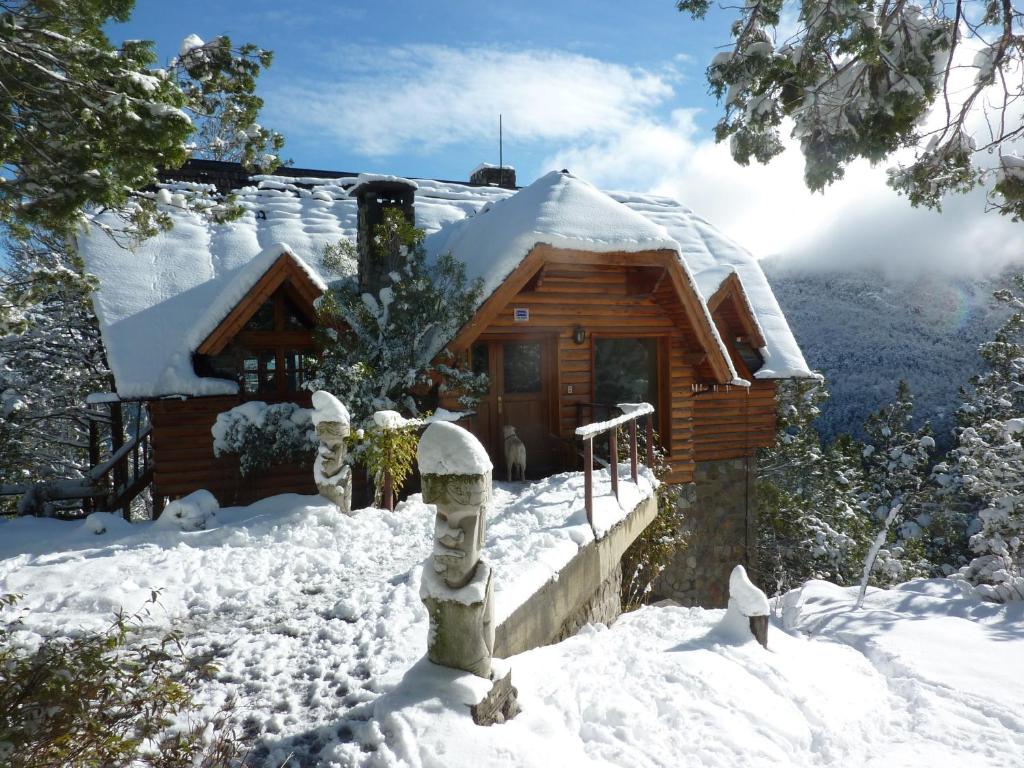 una cabaña cubierta de nieve frente a ella en Hostal Ayelen en San Martín de los Andes