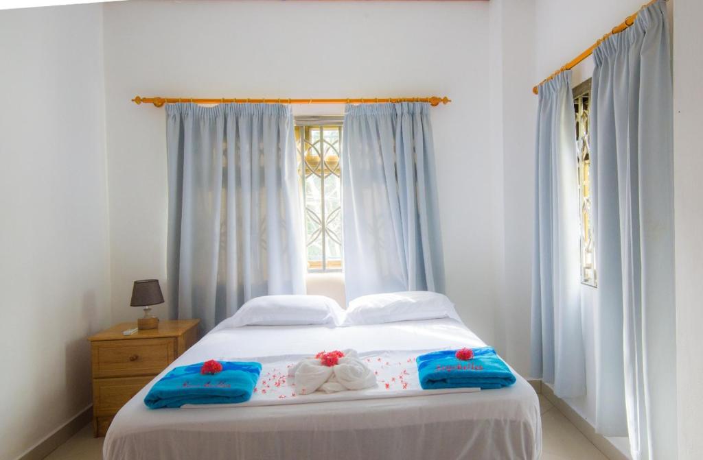 a bedroom with a white bed with blue towels and a window at Pascalo Villa Apartment in Mahe