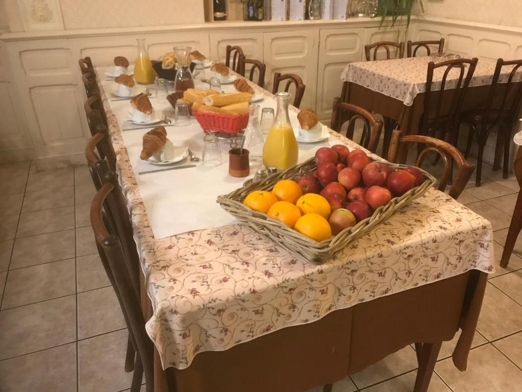a table with a basket of fruit on it at Hôtel Myosotis in Lourdes