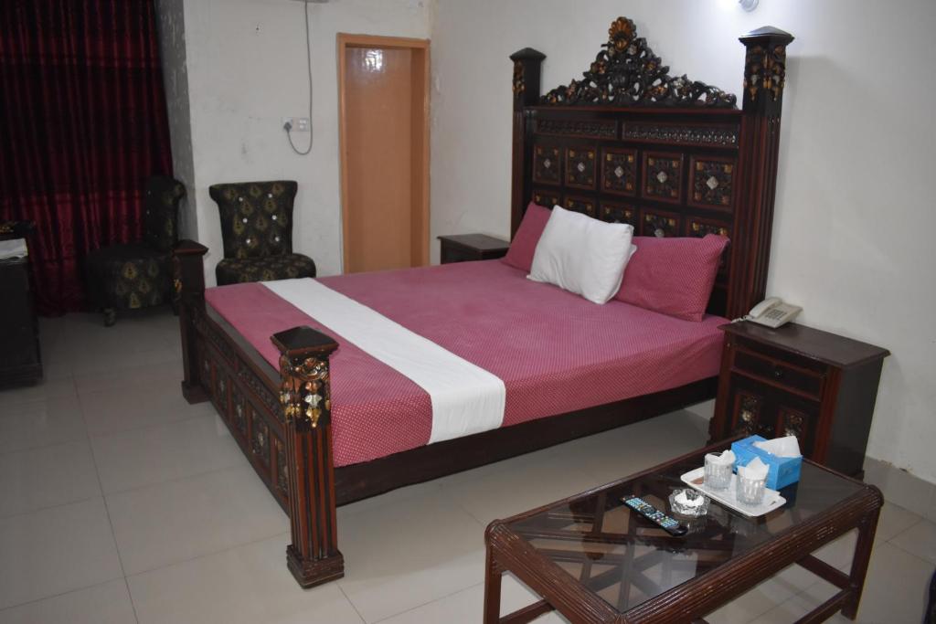 a bedroom with a large bed and a table at Hotel Basaira in Lahore