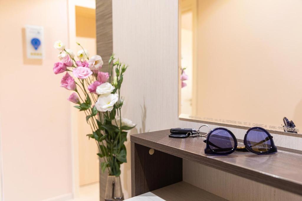 a pair of glasses and a vase of flowers on a counter at Central Point Apartments in Ruse