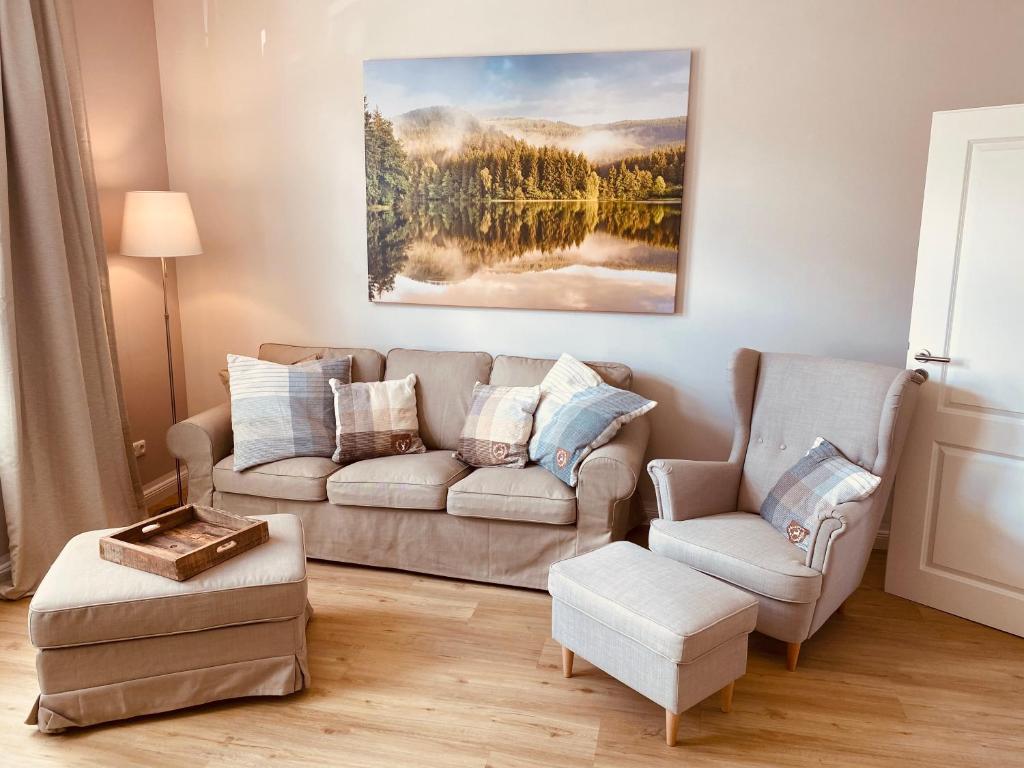 Mountain Suites Braunlage في برونلاغ: غرفة معيشة مع أريكة وكرسيين