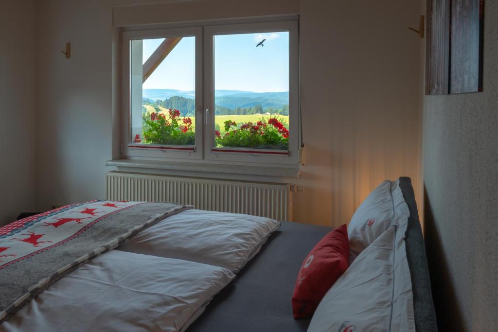 1 dormitorio con 1 cama y una ventana con flores en Ferienwohnung FUCHSBAU im EG des Ferienhauses Falkenhöhe, en Meuselbach-Schwarzmühle
