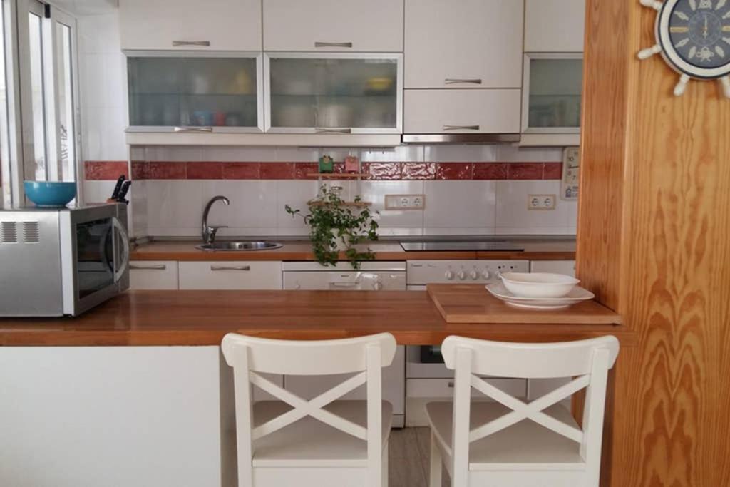 una cucina con armadi bianchi e sgabelli bianchi di Apartamento familiar a orillas del Mar Menor a Los Alcázares