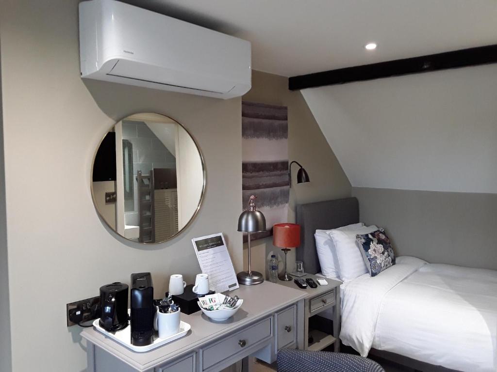 a bedroom with a bed and a dresser with a mirror at Rylands Farm Guest House in Wilmslow