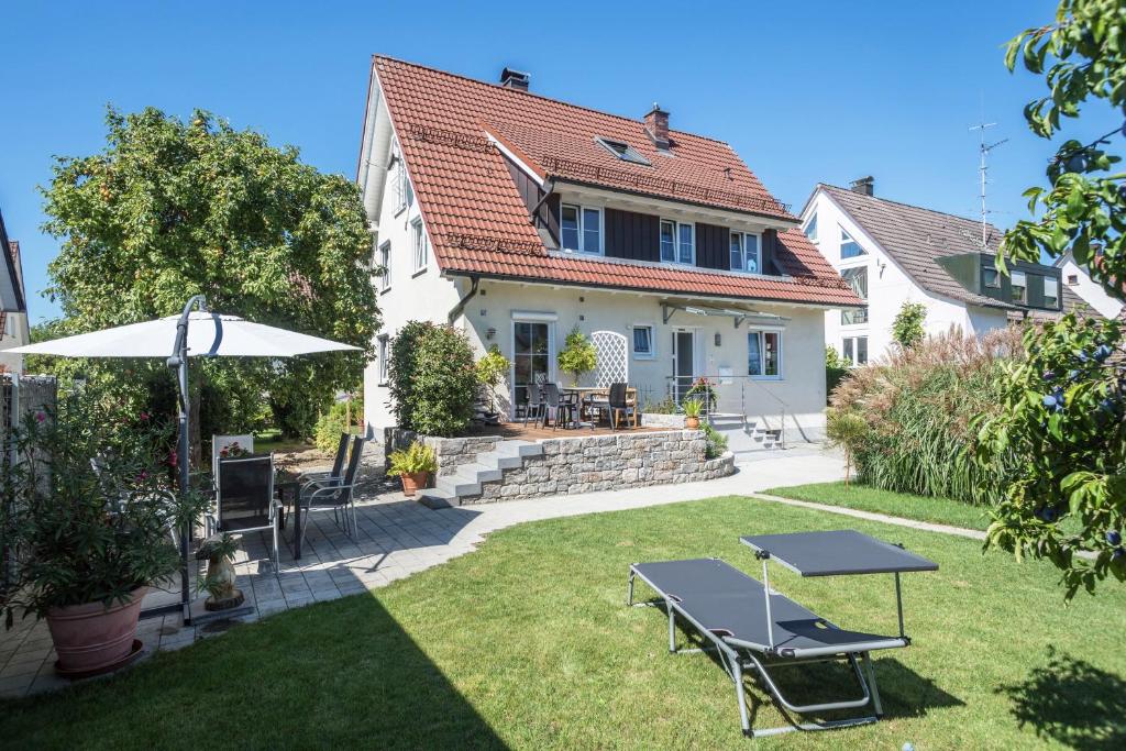 einen Hinterhof mit einem Tisch und einem Sonnenschirm in der Unterkunft Haus Sonnenschein in Eriskirch