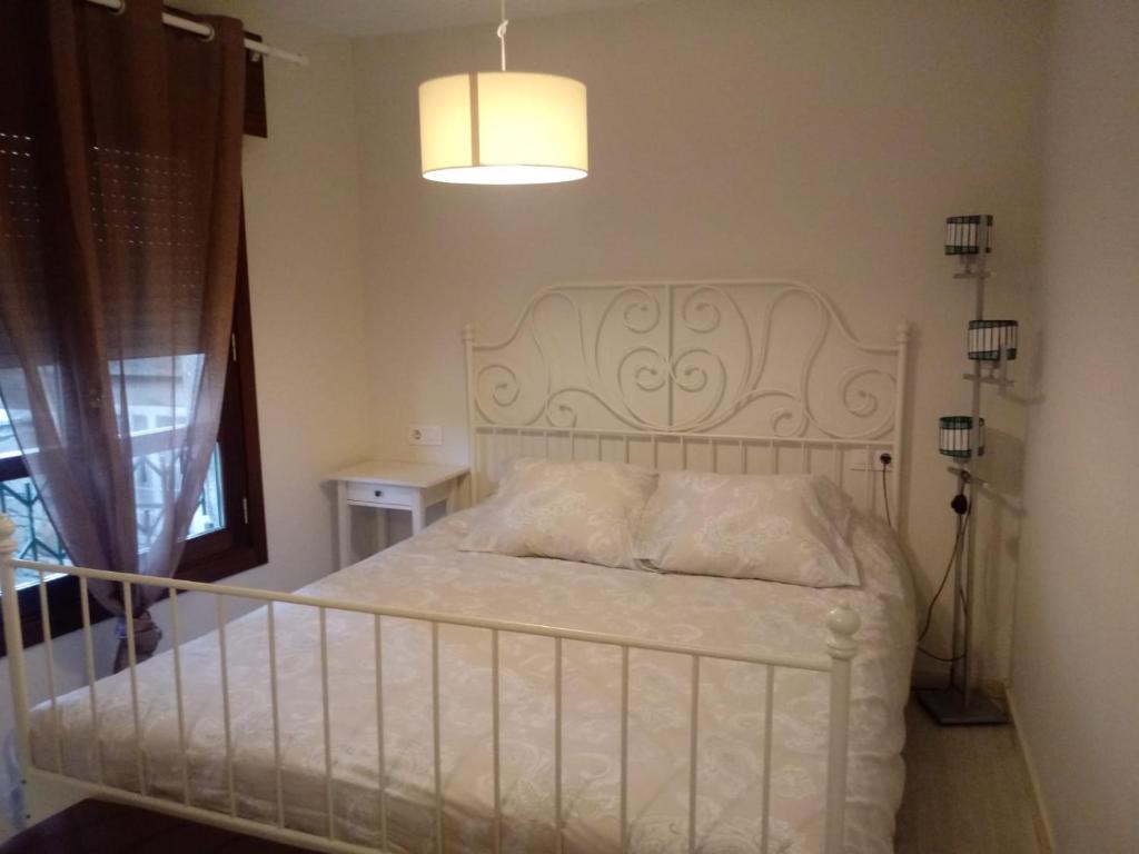 a white bed in a bedroom with a lamp at Casa Marinera "Tu casa de Baiona" in Baiona