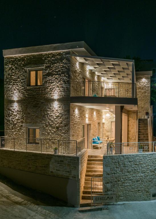 a stone house with a balcony at night at Efkosmias Apartments in Pitsidia