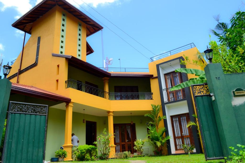 una casa amarilla con una puerta verde en Villa16Hikkaduwa, en Hikkaduwa