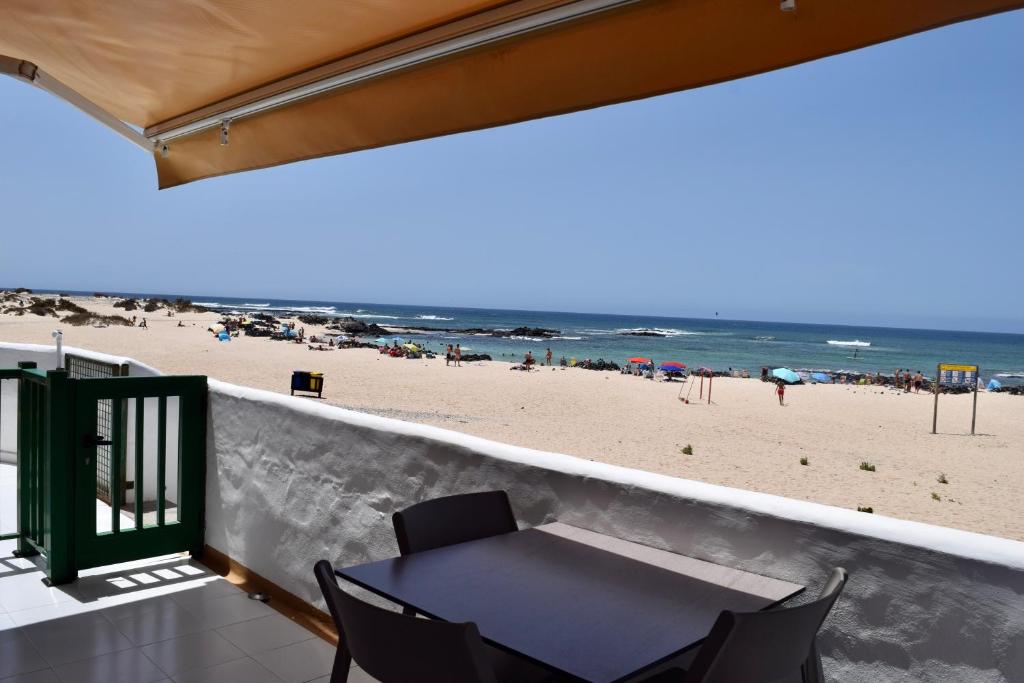 un tavolo e sedie su un balcone con spiaggia di Beachfront Bungalow Cotillo Lagos a Cotillo