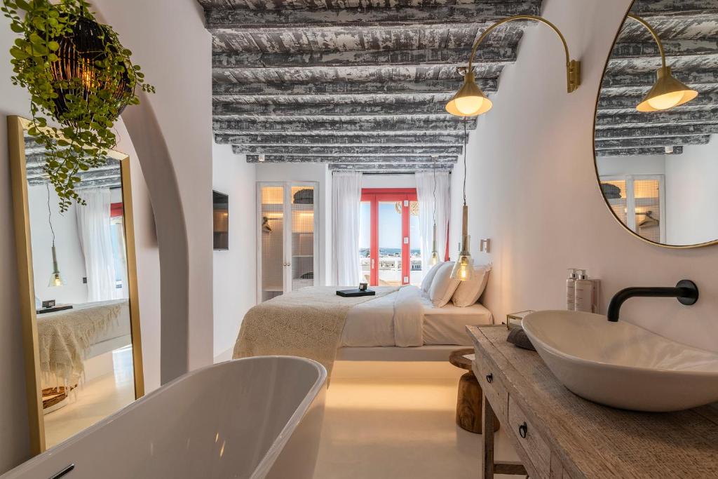 a bathroom with a tub and a bed and a sink at The TownHouse Mykonos in Mýkonos City
