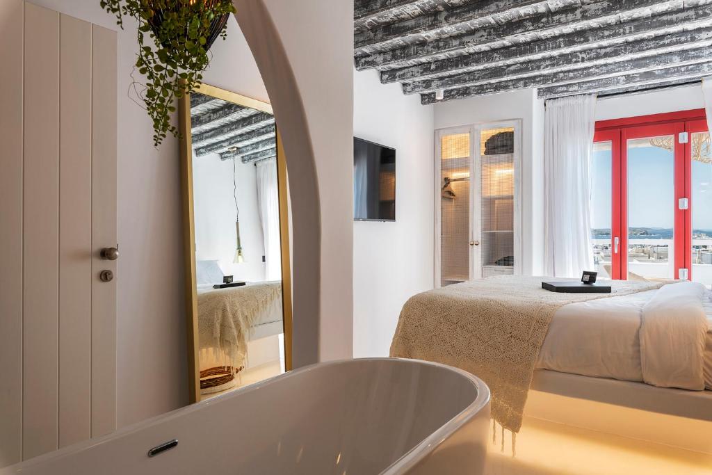 a bathroom with a tub and a bed and a mirror at The TownHouse Mykonos in Mýkonos City