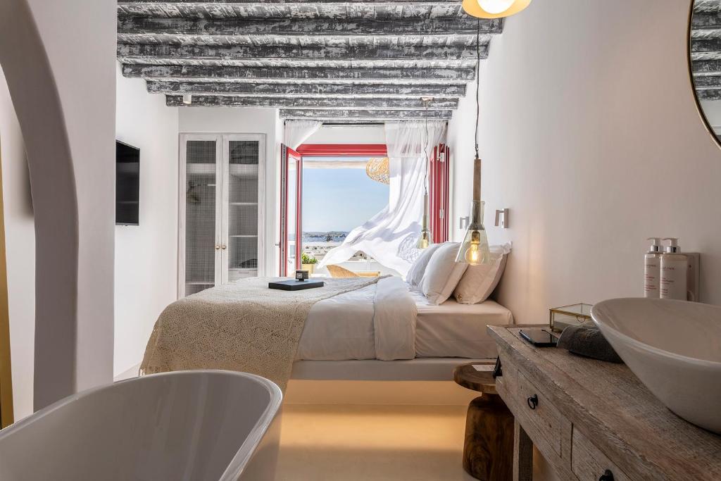 a bedroom with a bed and a sink and a tub at The TownHouse Mykonos in Mýkonos City