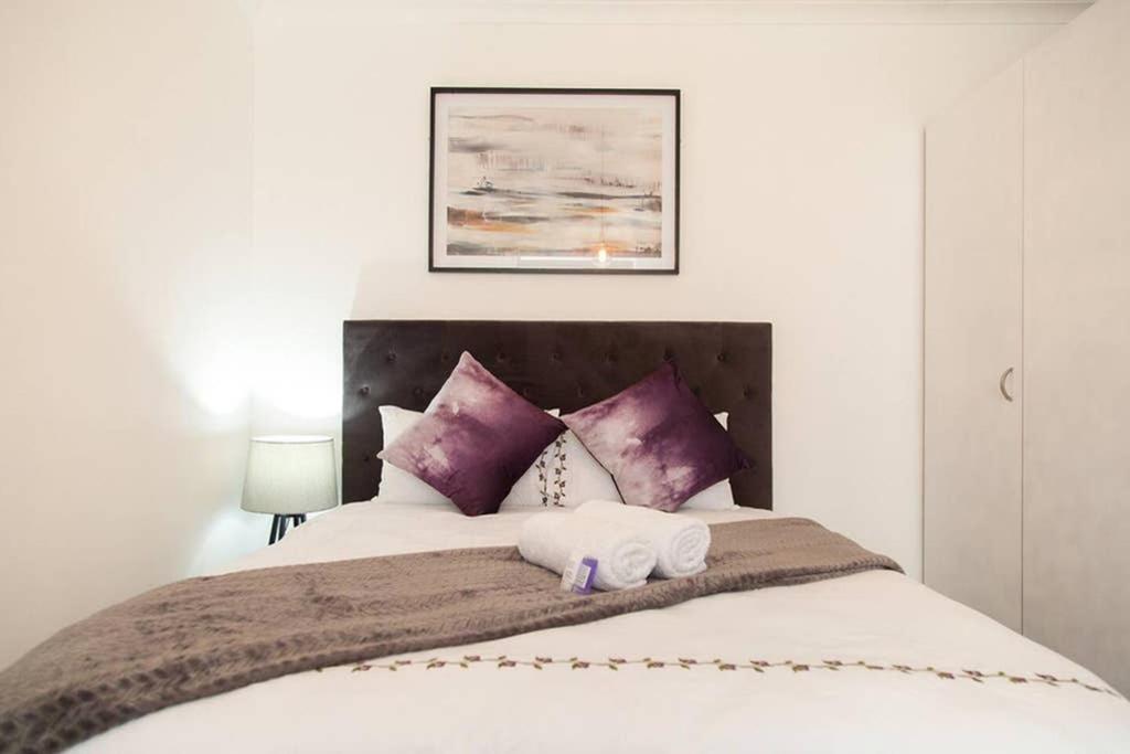 um quarto com uma cama grande e almofadas roxas em The Square Holiday Apartments em Cidade do Cabo